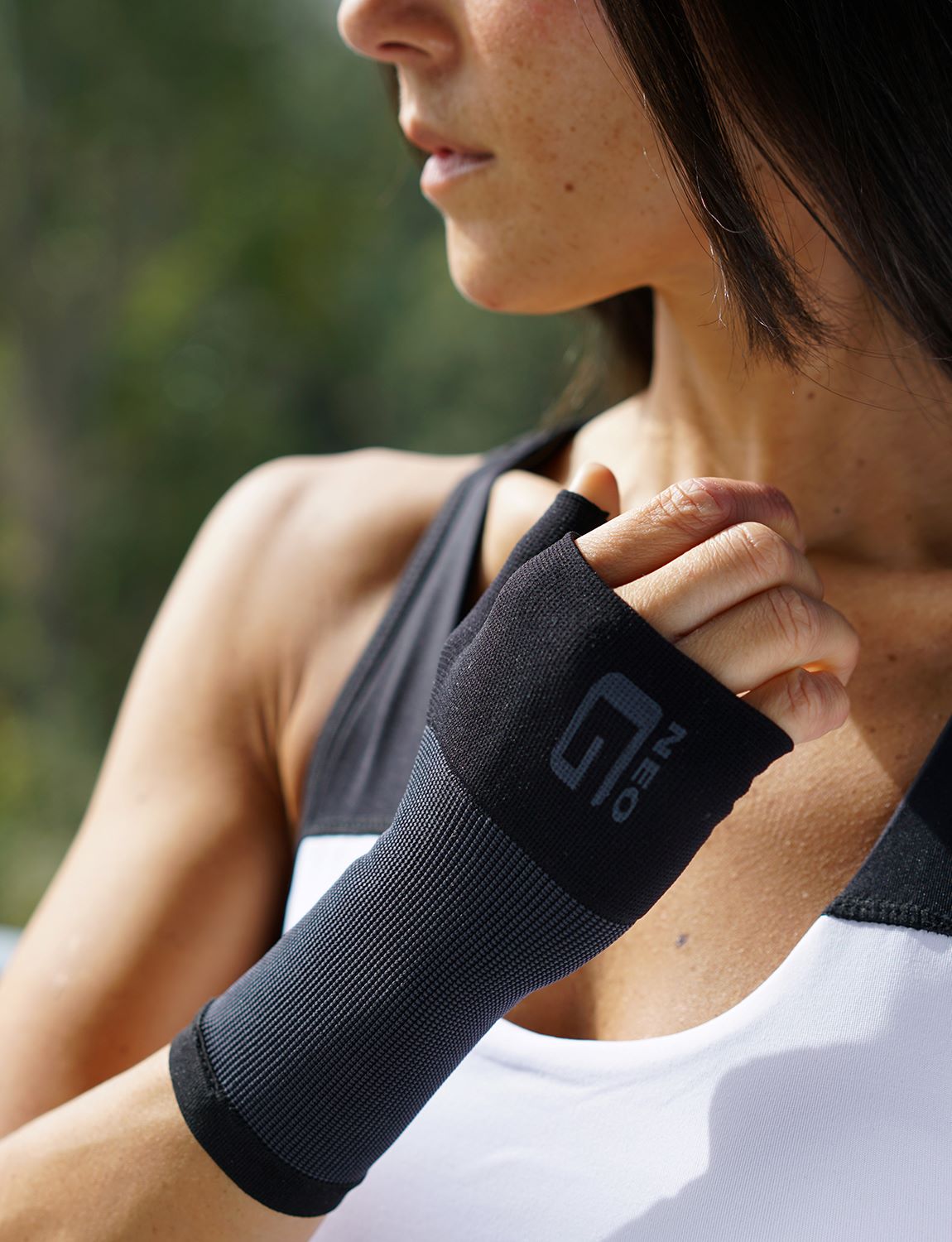 Woman wearing black Neo G Airflow Wrist & Thumb Support on right hand, ready for exercise